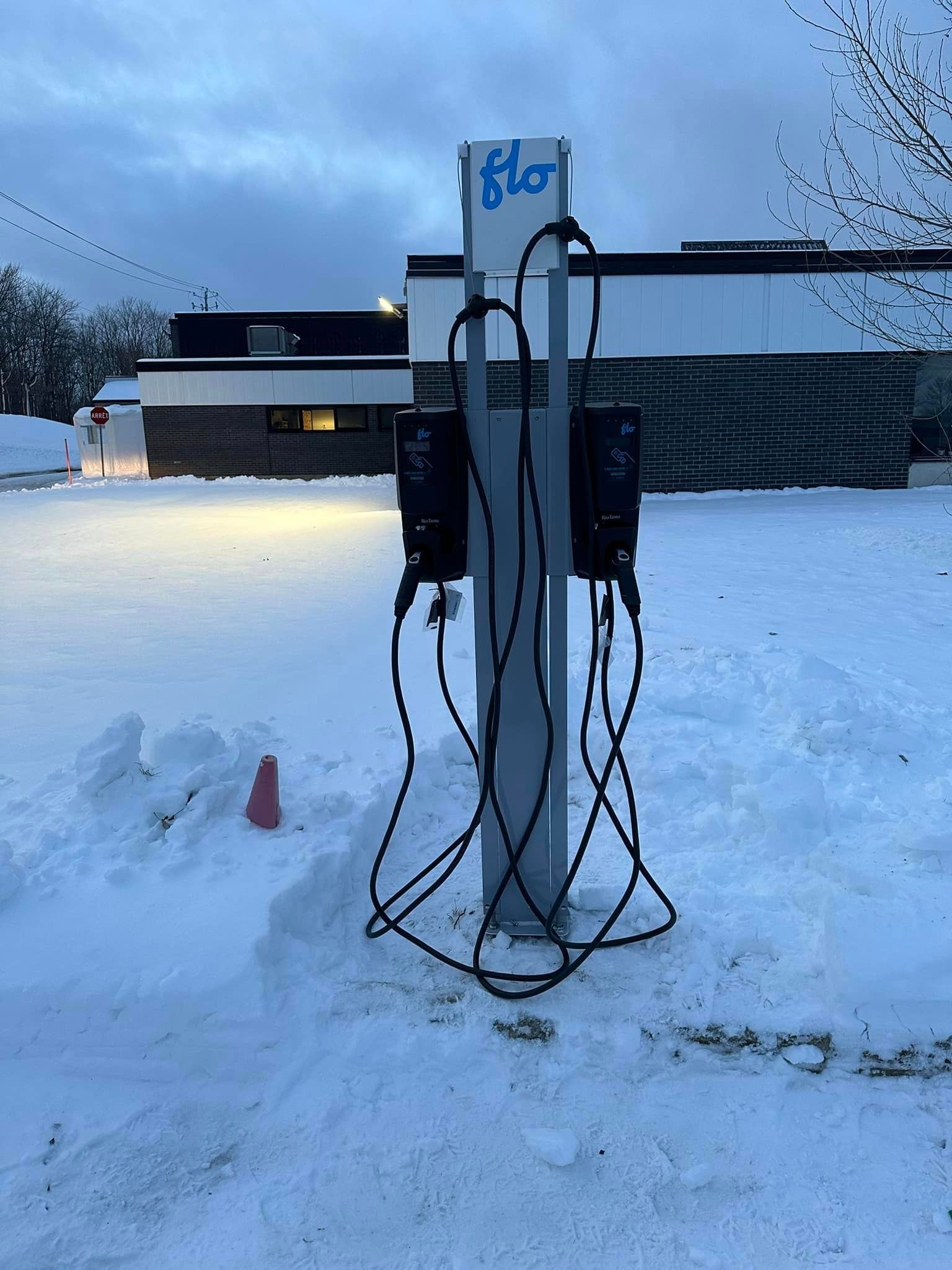Une borne de recharge dans la neige avec le mot flo dessus