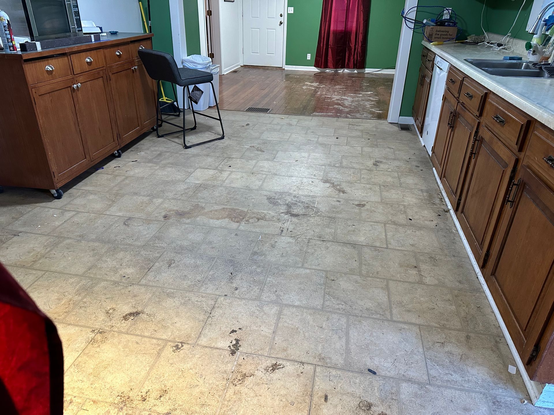 A kitchen with a dirty tile floor and wooden cabinets.