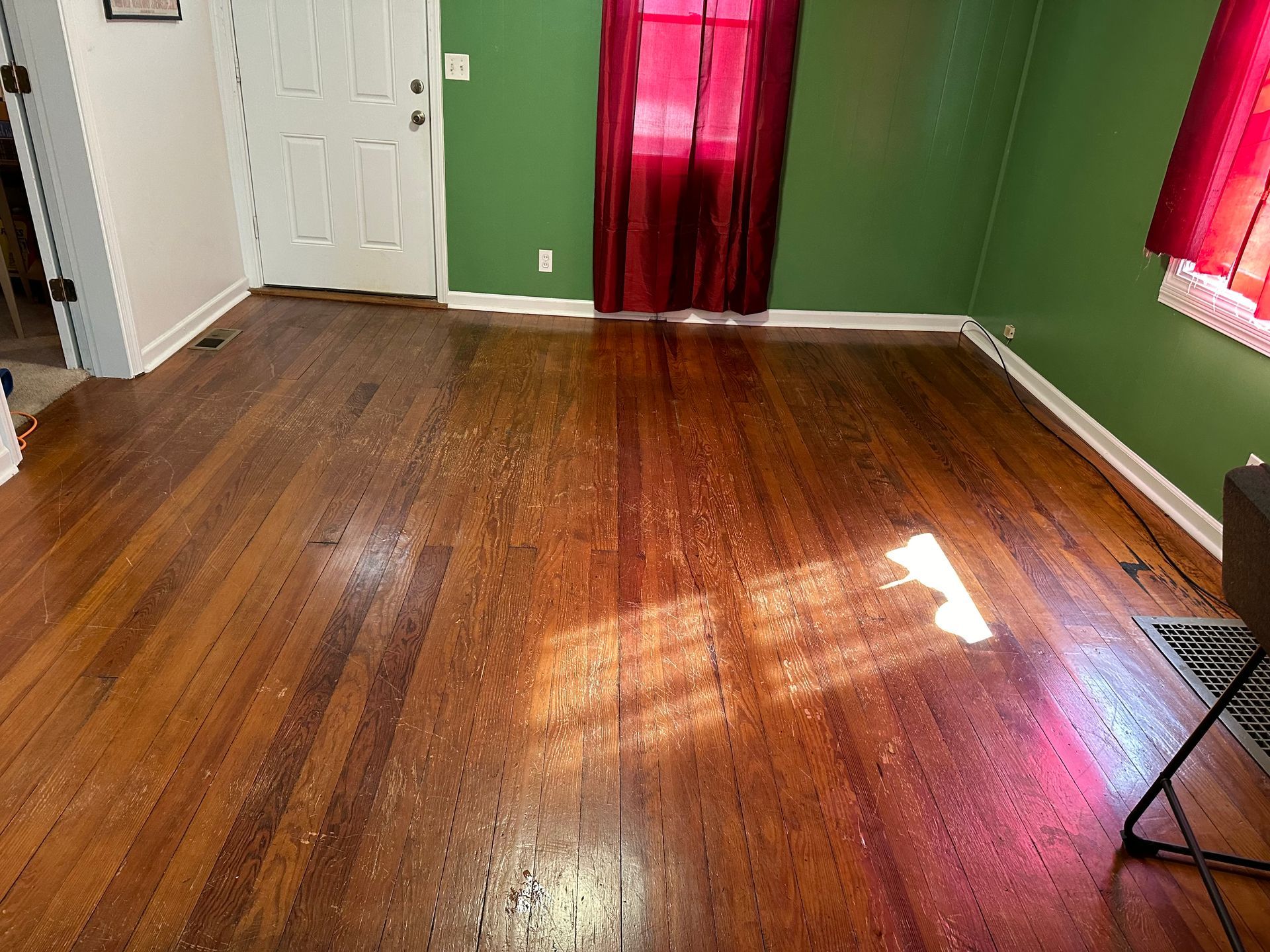A living room with a wooden floor and green walls.