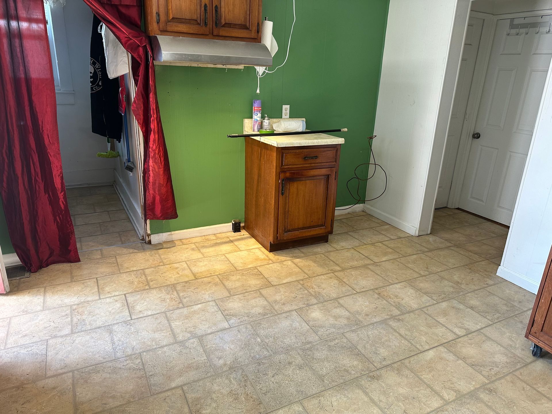 A kitchen with a green wall and a wooden cabinet.