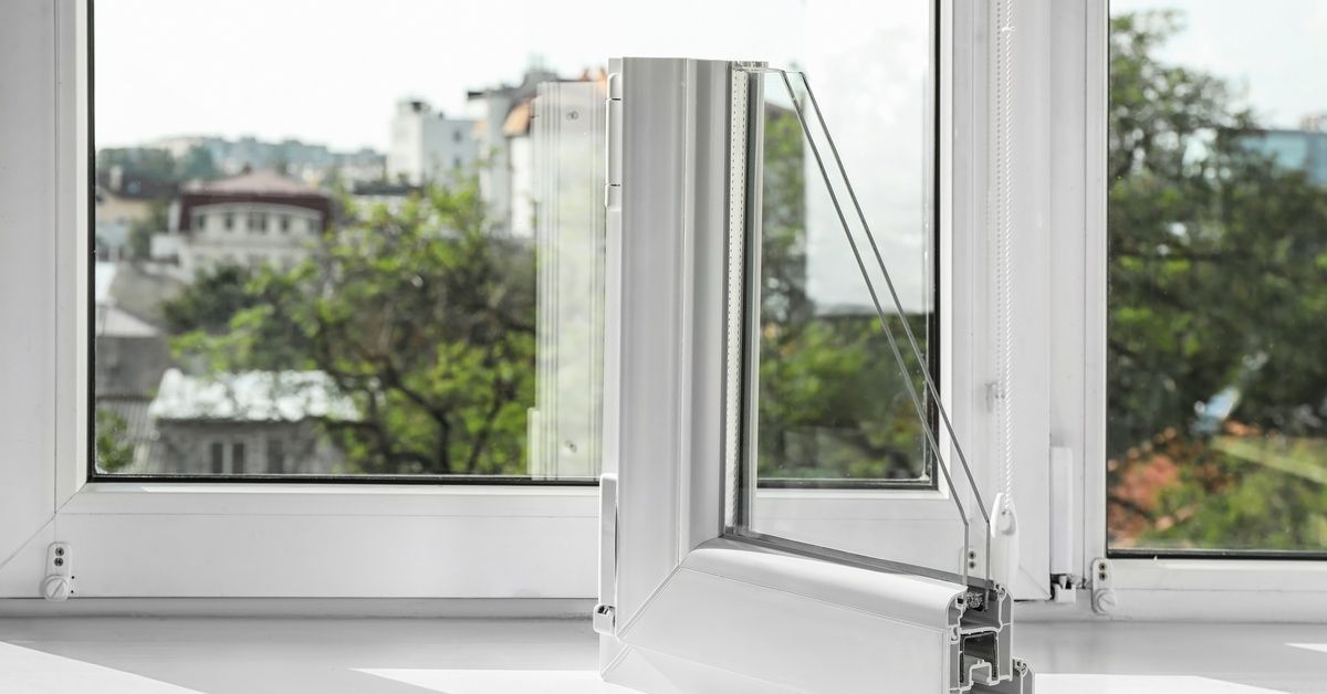 A sample of a double-pane window interior sits on a white sill beside a window overlooking a city skyline.