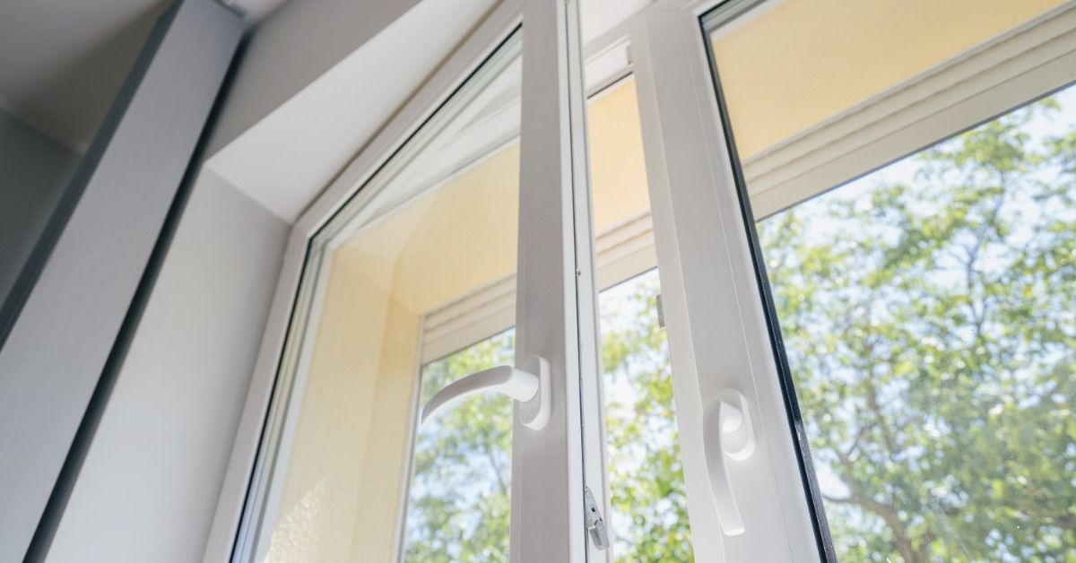 A white-framed window stands partially open, letting natural light in while showing trees and a clear sky outside.