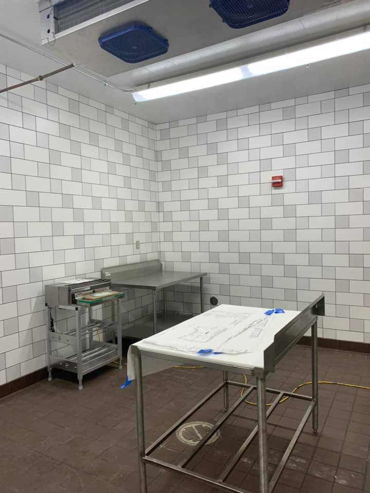 A sterile, tiled room with stainless steel tables and equipment; likely a commercial kitchen or food prep area.
