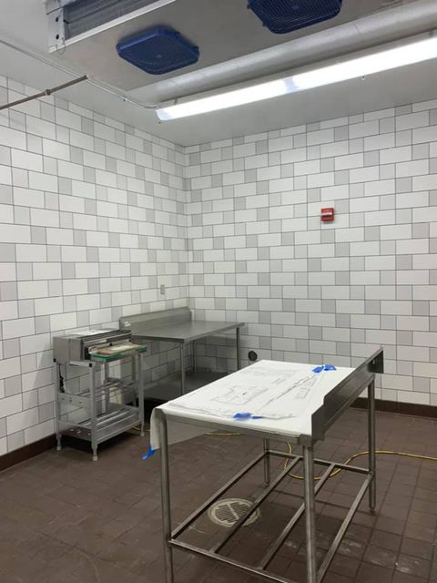 A mortuary with tiled walls, stainless steel tables, and medical equipment.