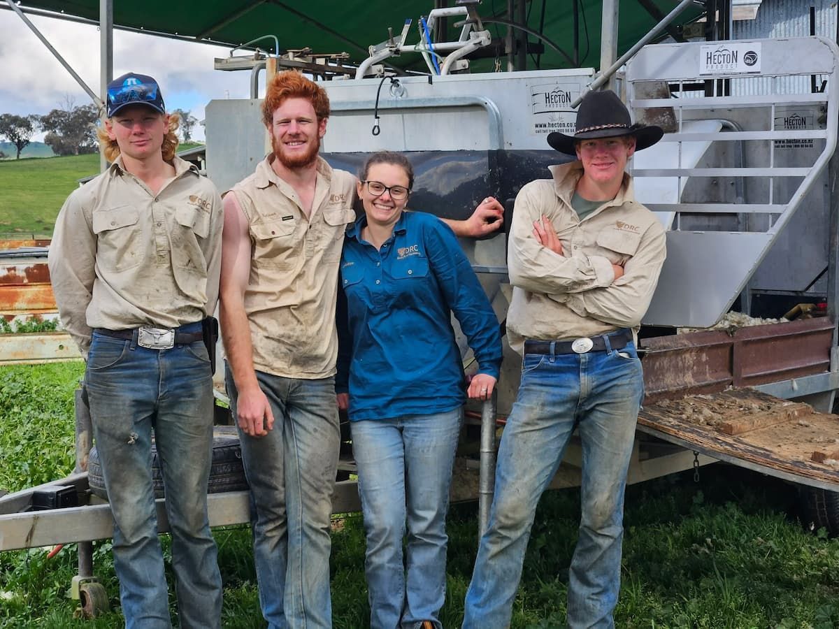 Four People Stand in Front of a Boat, Wearing Work Clothes and Smiling Outdoors — Dusty Rural Contracting in Coolac, NSW