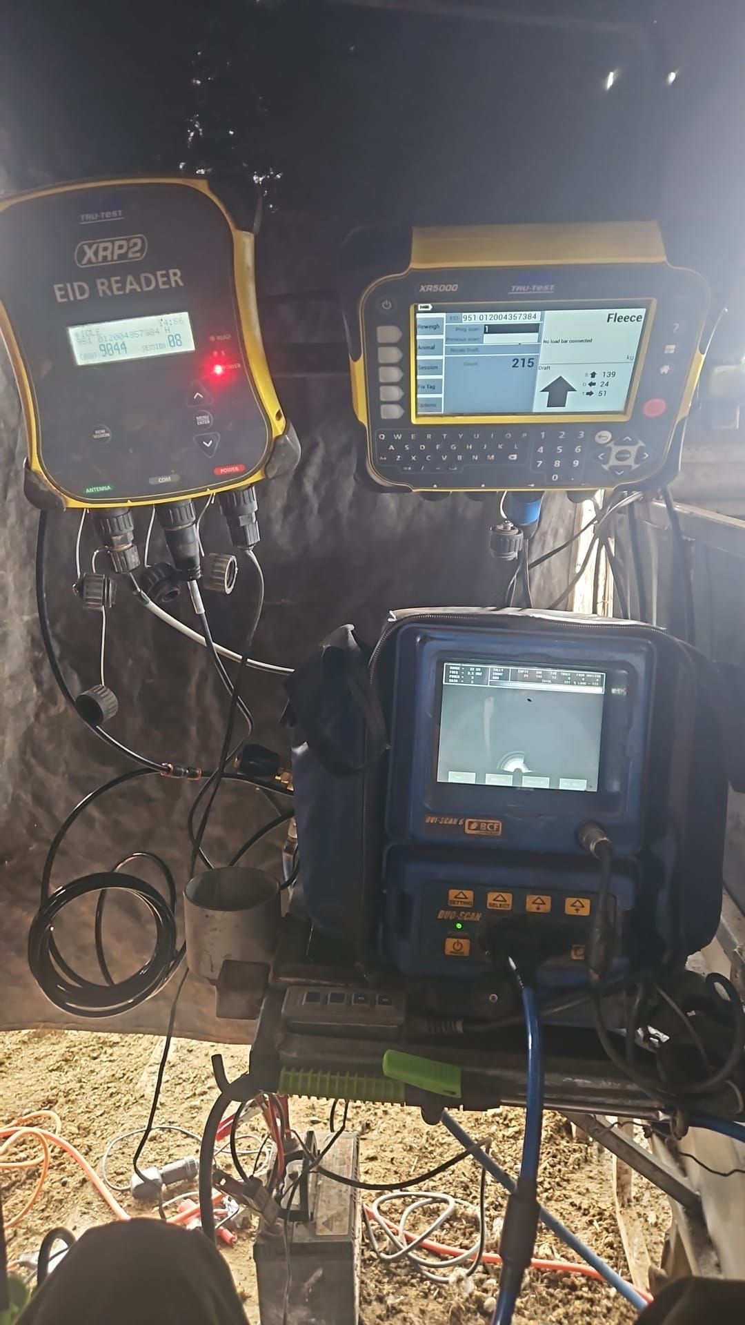Three mounted industrial control displays in a dark equipment room, showing graphs and status screens. — Dusty Rural Contracting in Coolac, NSW