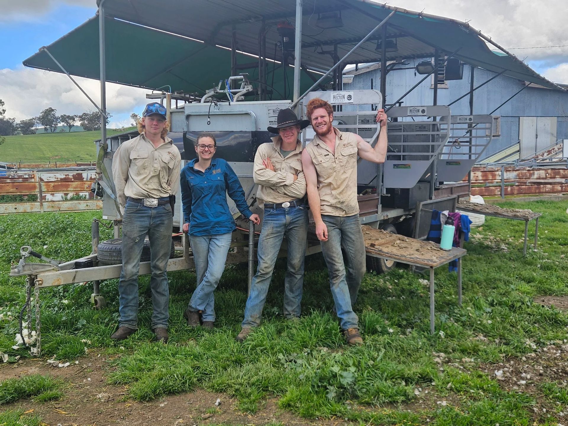 Four people stand on a small farm platform with a large gray machine under a canopy. — Dusty Rural Contracting in Coolac, NSW
