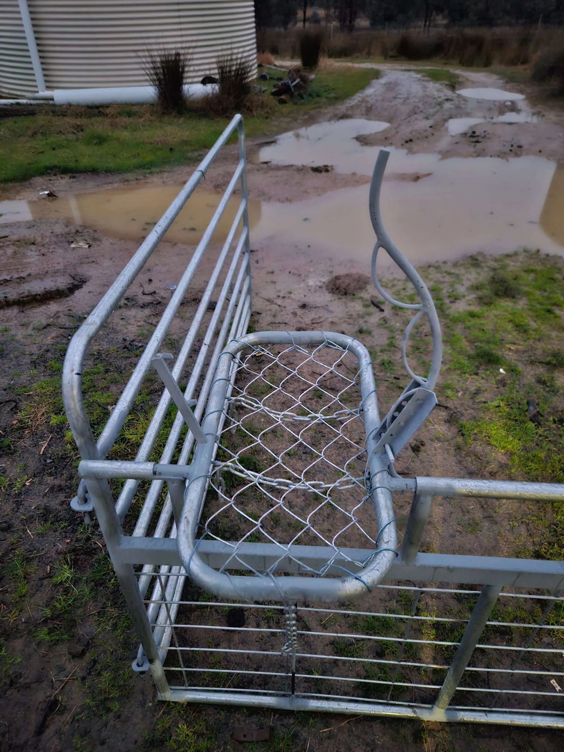 Damaged metal cart tipped over on muddy ground near puddles and a dirt path — Dusty Rural Contracting in Coolac, NSW