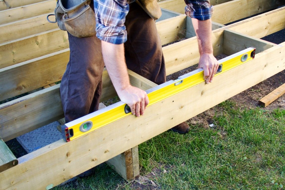 Contractors installing planks on a new wooden deck.