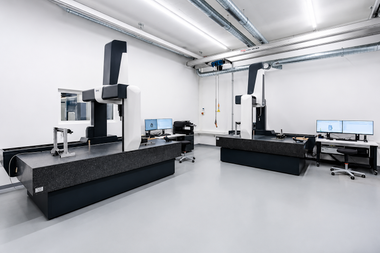Laboratoire industriel moderne avec bras robotisés, postes de travail et ordinateurs dans une pièce blanche et lumineuse