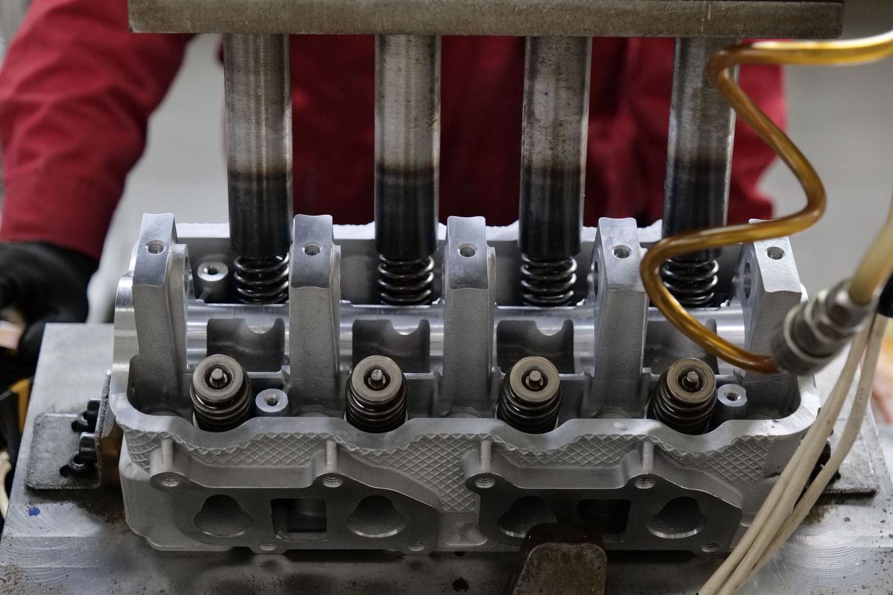 Gros plan sur une culasse de moteur avec quatre ressorts de soupape et les durites qui y sont rattachées lors de la maintenance