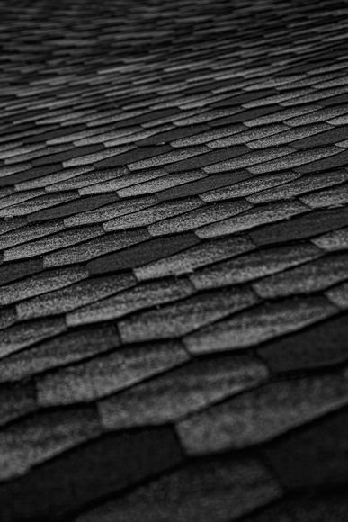 Gros plan sur des bardeaux de toiture gris foncé se chevauchant avec un motif diagonal texturé