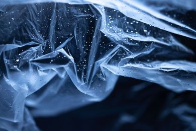 Feuille de plastique translucide bleue avec des plis froissés et de minuscules gouttelettes d'eau