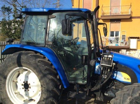 Trattore blu parcheggiato accanto a un edificio giallo.