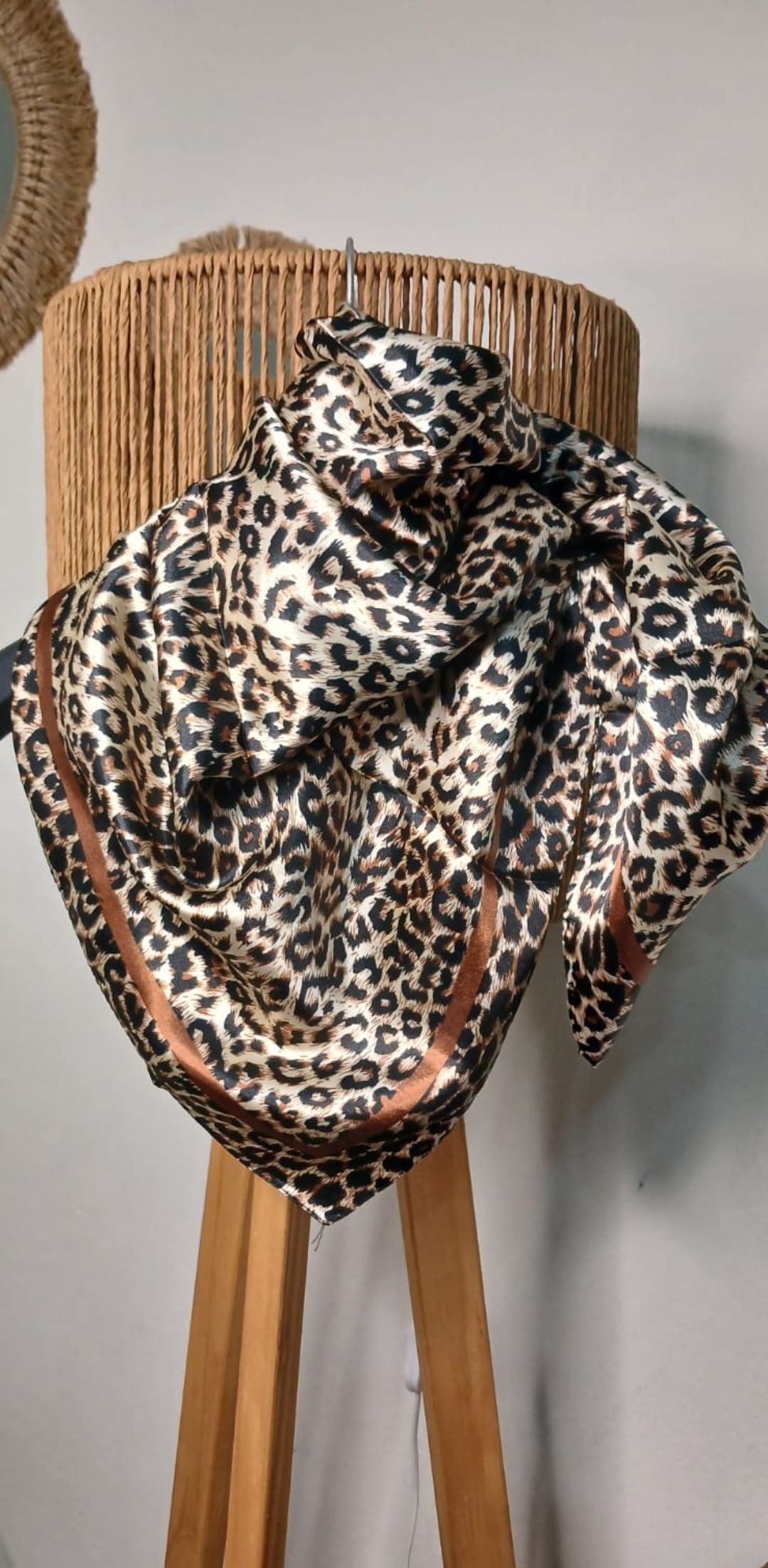 Bufanda con estampado de leopardo colocada sobre una silla de madera en una habitación.