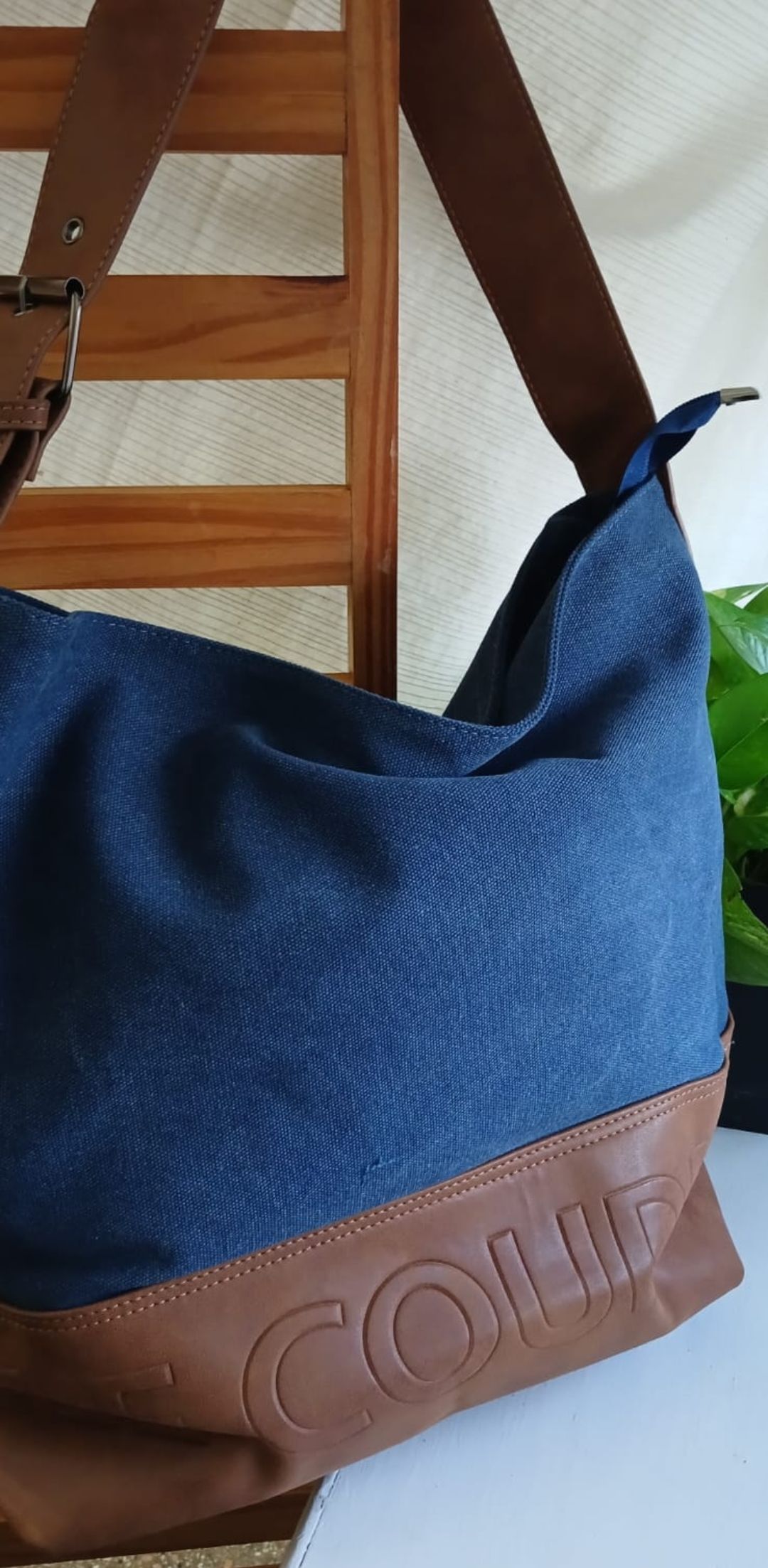 Bolso de mano de piel azul y marrón con la inscripción “CELINE” grabada en la parte inferior, colgado en el interior.