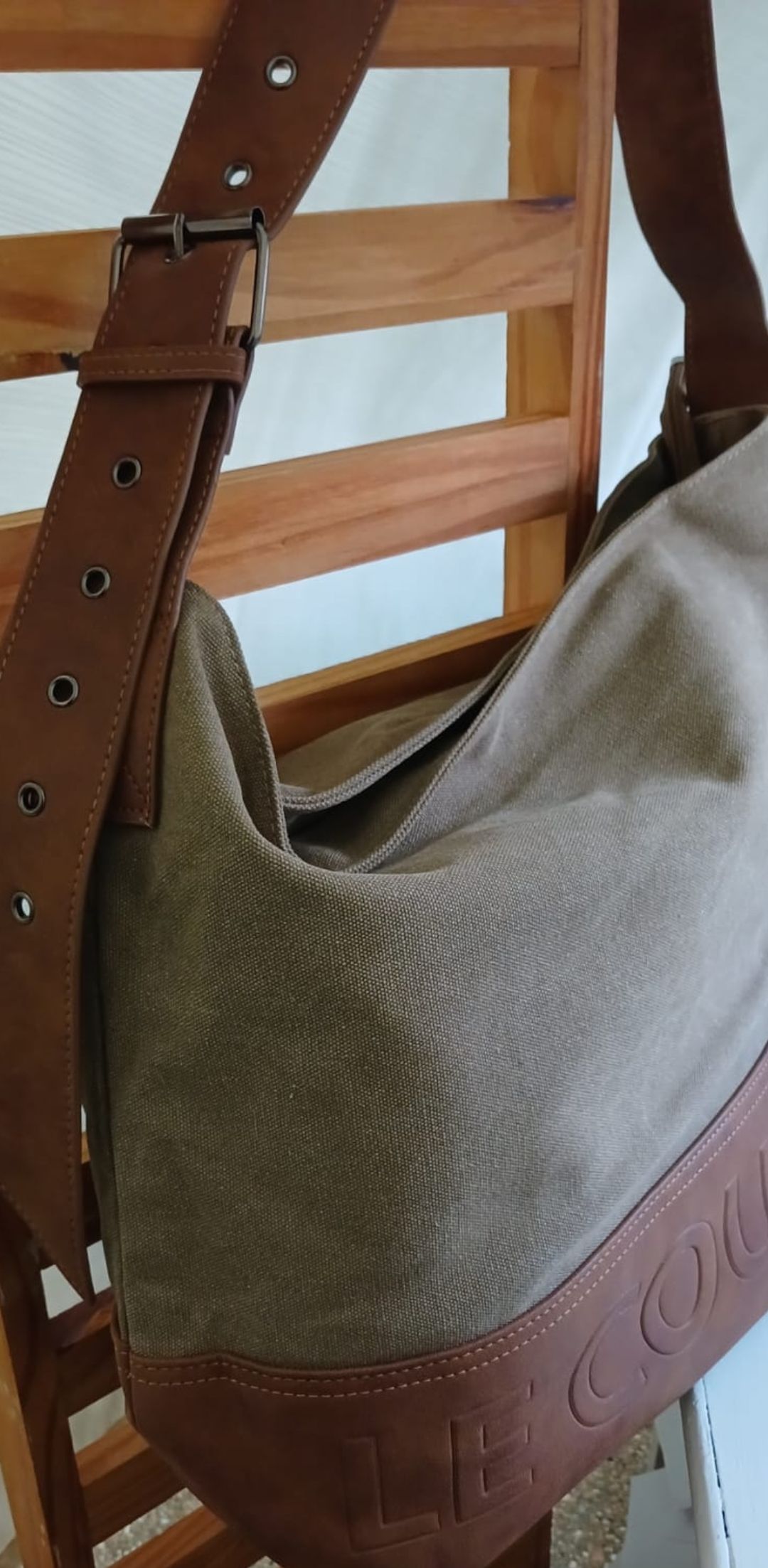Bolso de mano de piel azul y marrón con la inscripción “CELINE” grabada en la parte inferior, colgado en el interior.