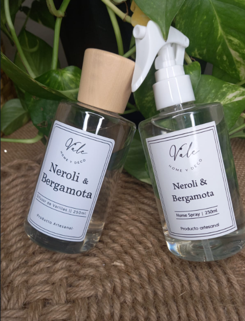 Dos frascos de perfume “Neroli & Bergamota” sobre tela tejida, y un frasco de vidrio transparente con tapón de madera.