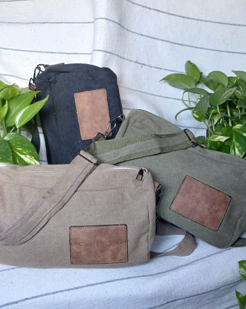 Varias bolsas y estuches de lona en color negro, verde oliva y beige con etiquetas de parche marrones sobre una silla.