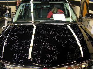 A black car with a lot of bubbles on the hood