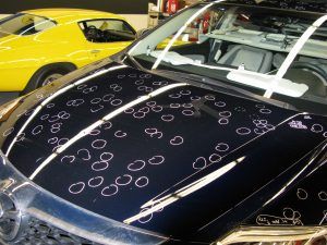 A black car with a lot of dents on the hood