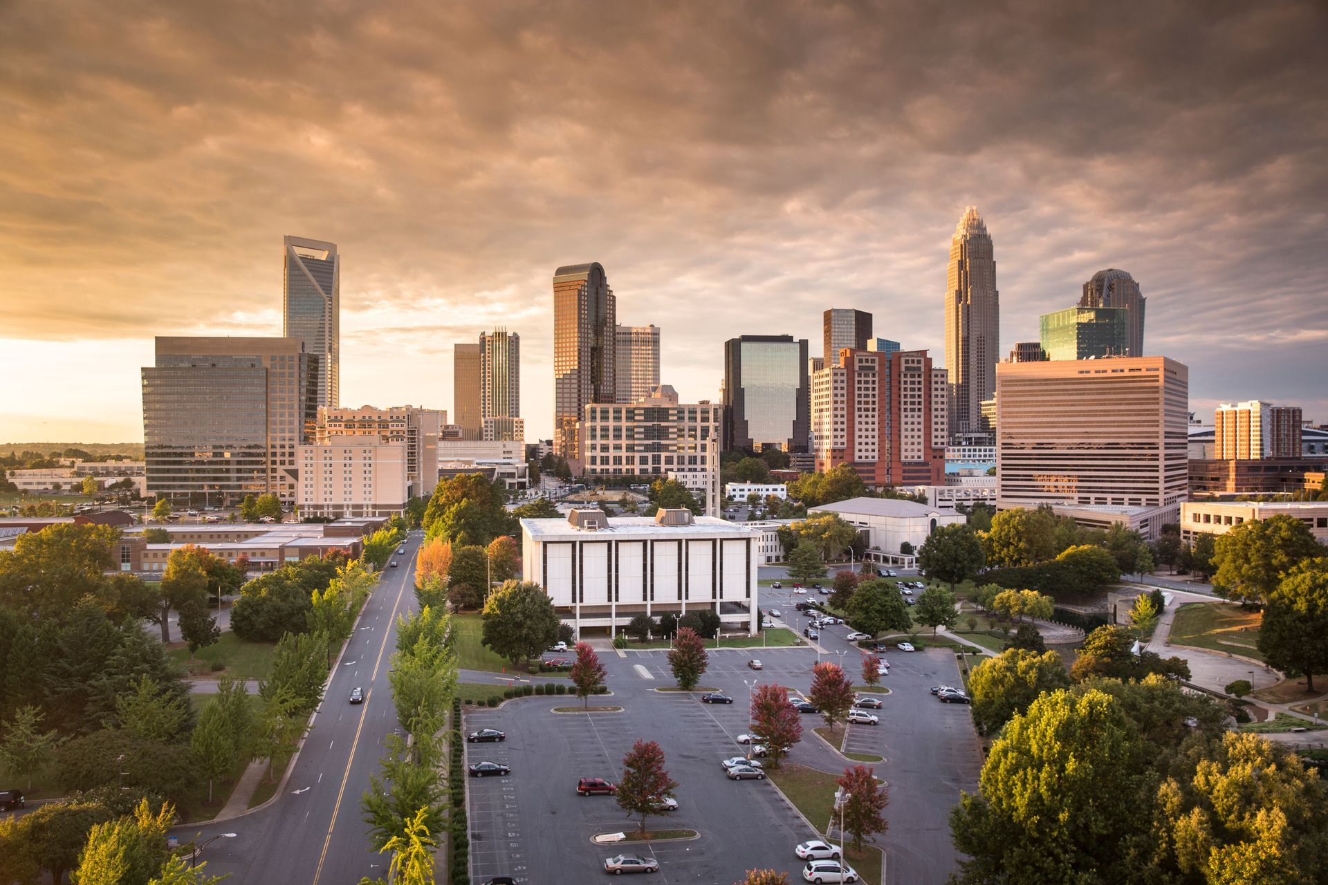 Downtown skyline at sunset with a parking lot and tree-lined streets in the foreground Downtown city skyline at sunset with a parking lot and trees in the foreground