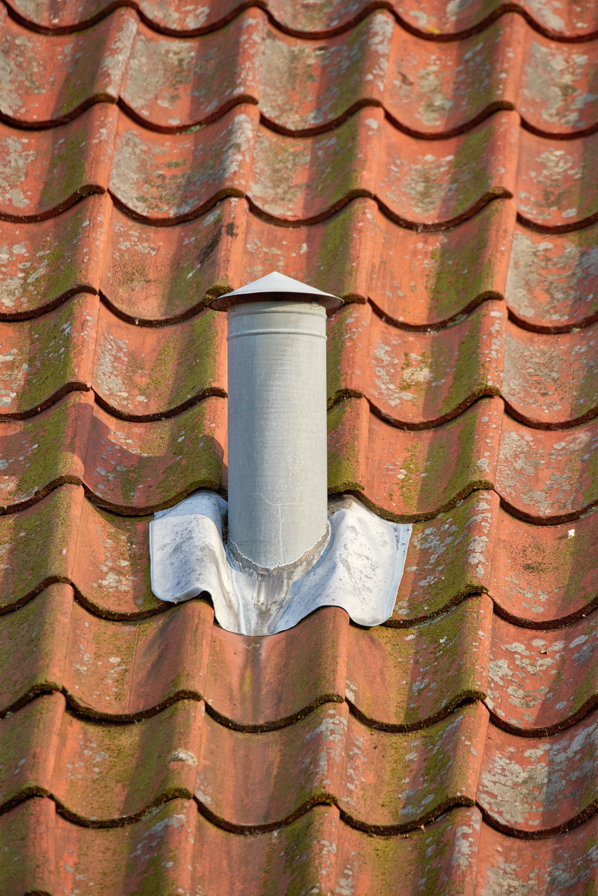 Red tiled roof with a silver metal chimney pipe Red tiled roof with a silver metal chimney pipe