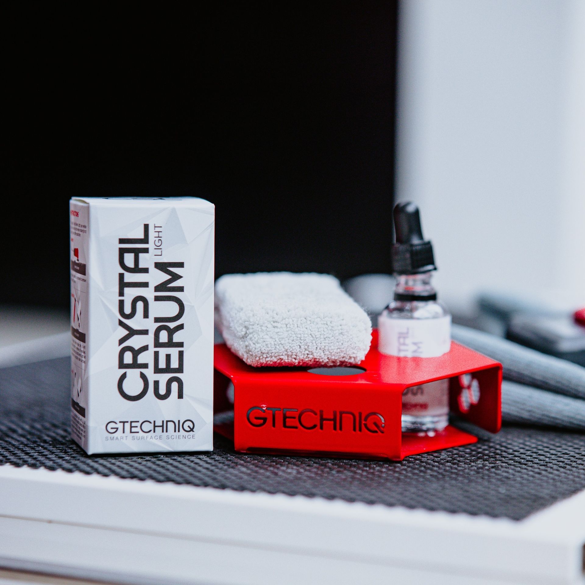 GTECHNIQ Crystal Serum box and bottle on a red stand with a white applicator pad.