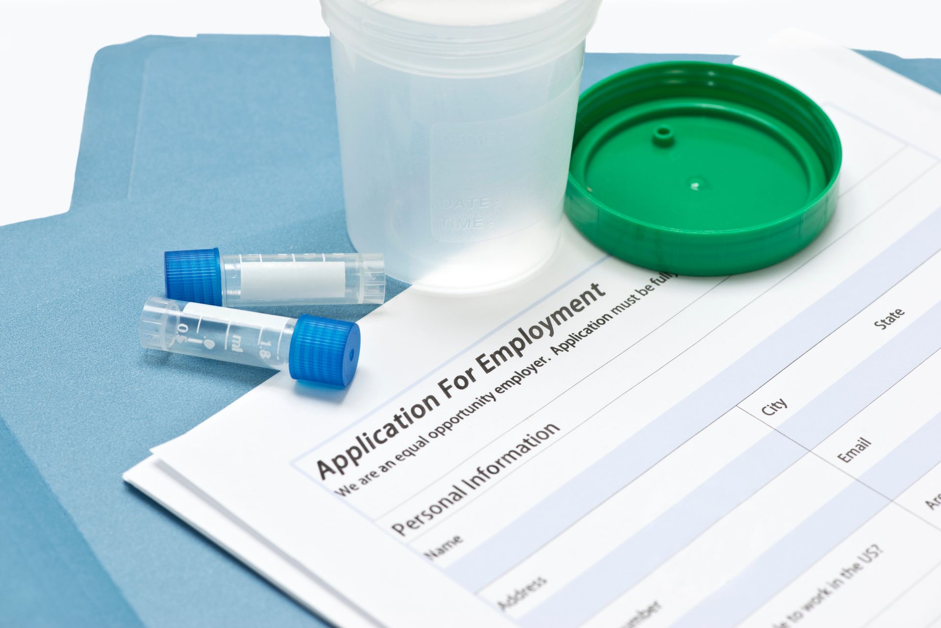 A job application surrounded by drug testing materials and blue folders. A job application surrounded by drug testing materials and blue folders.