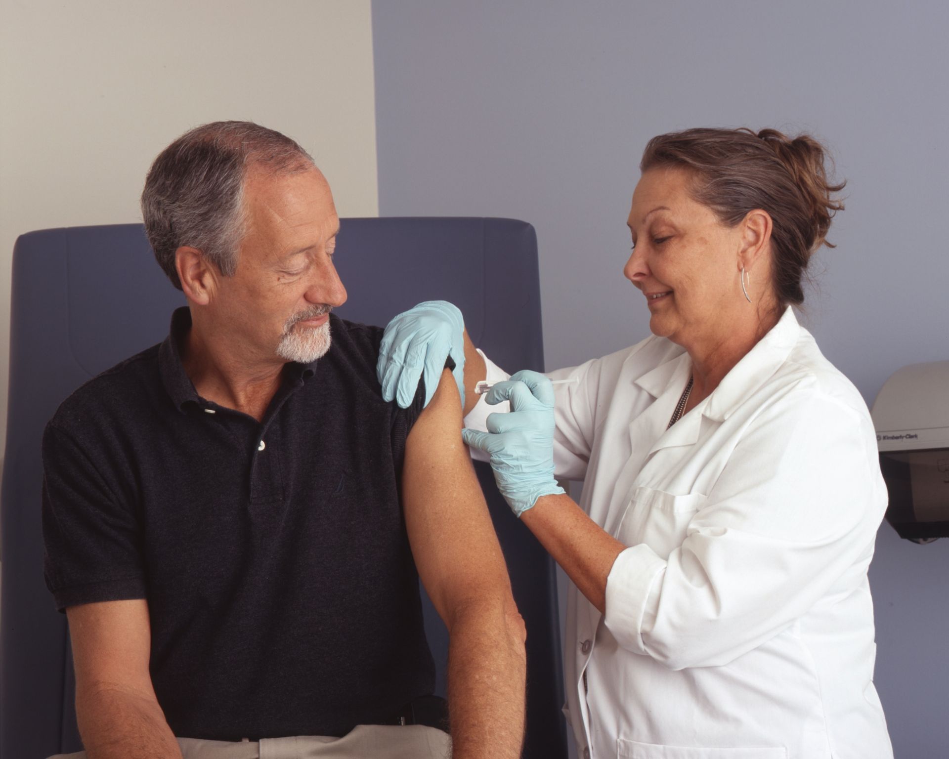 Nurse administering an injection to a patient's arm in a medical setting.