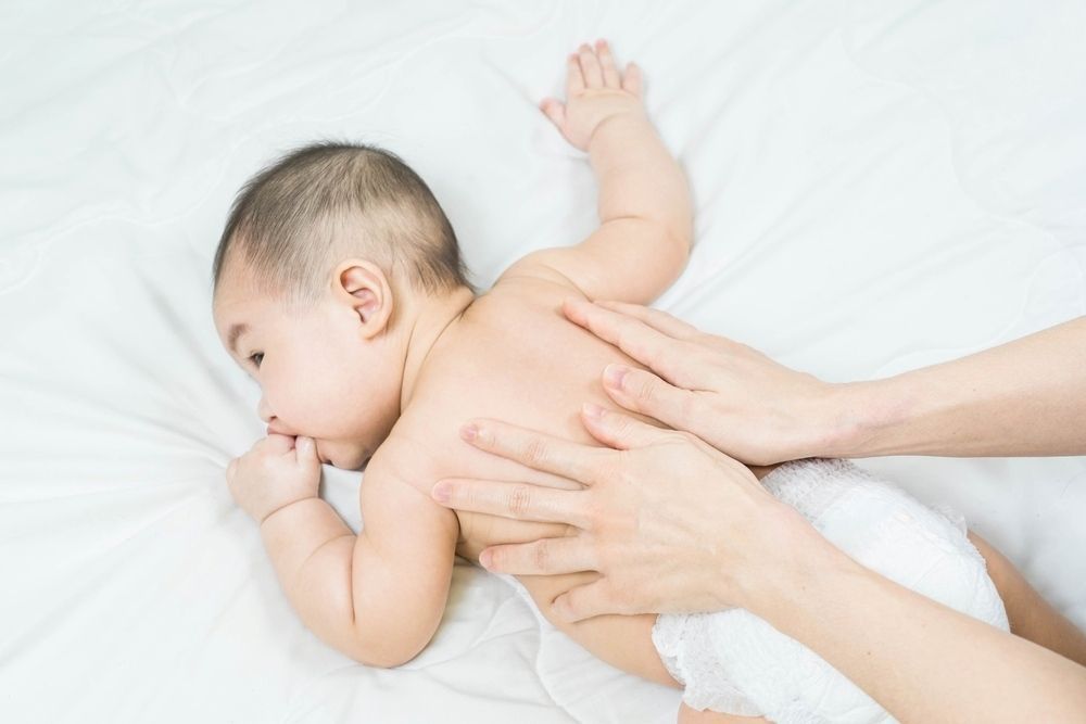 A Woman is Giving a Baby a Massage on a Bed — Life24 Health Bowen Therapy In Lavington, NSW