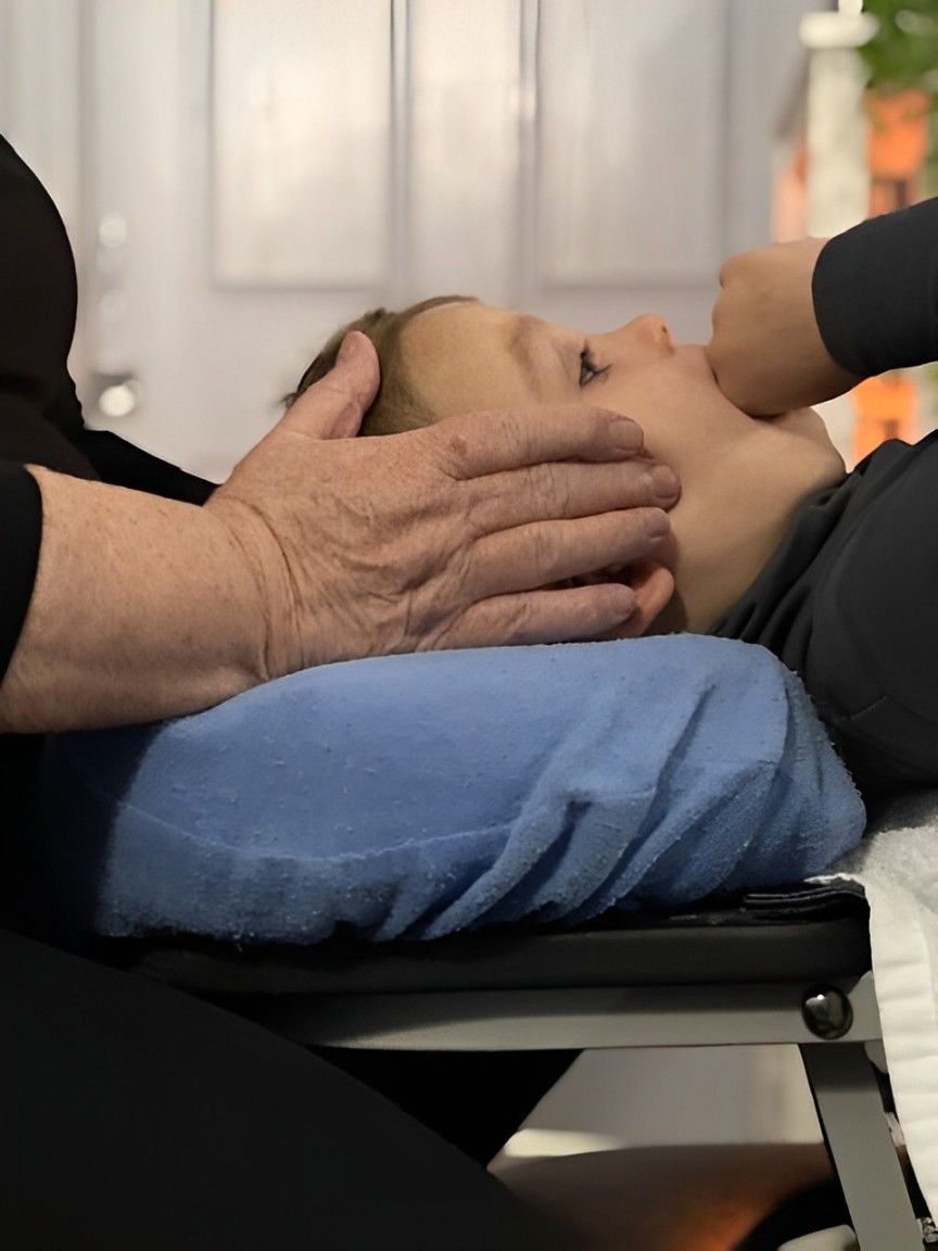 A Child Is Laying On A Blue Pillow With A Person's Hands On It — Life24 Health Bowen Therapy In Lavington, NSW