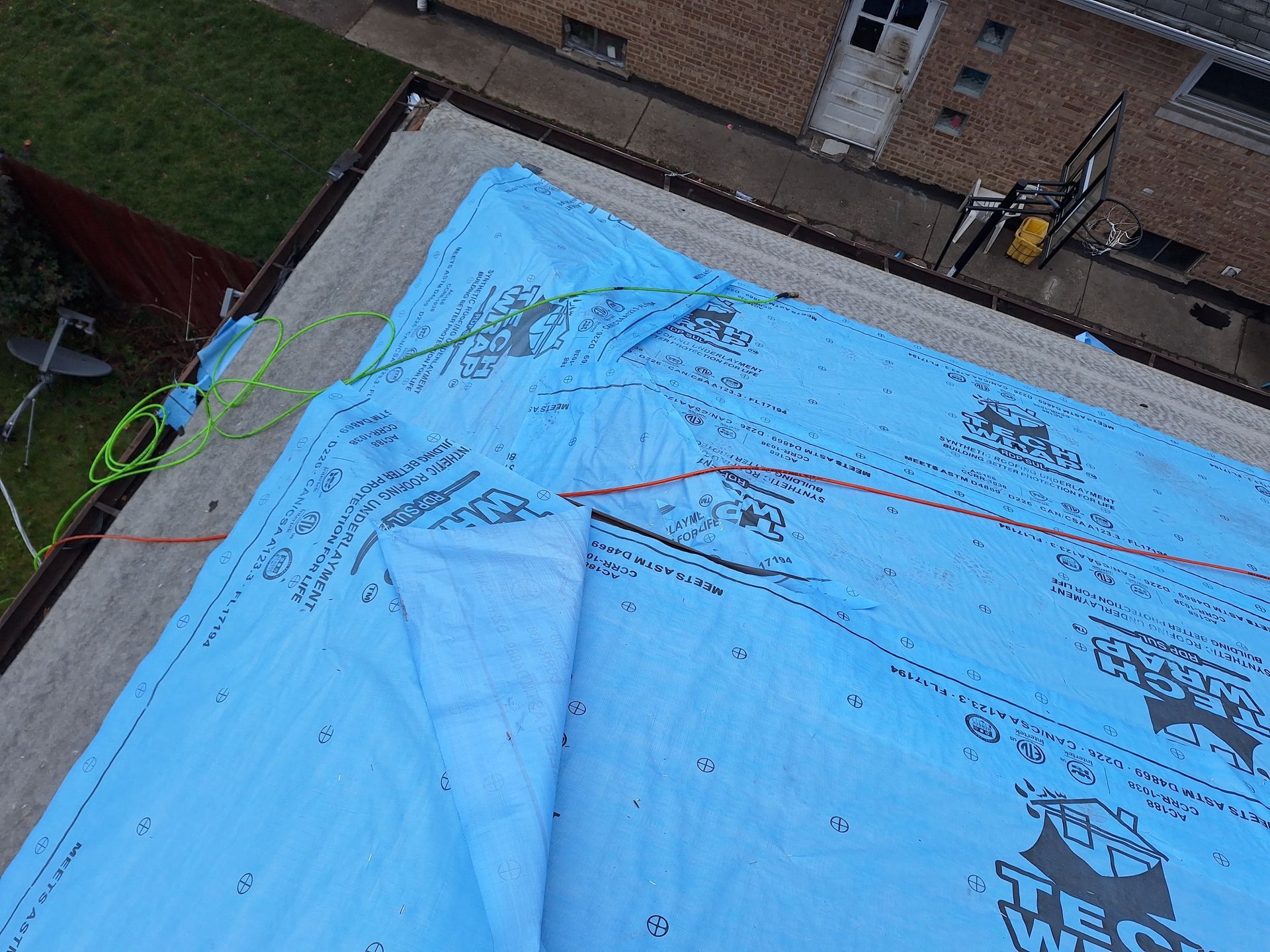 An aerial view of a roof with a blue tarp on it.