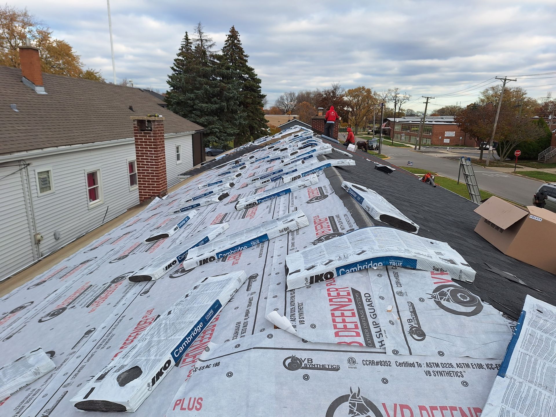 The roof of a house is being covered with a roofing material.