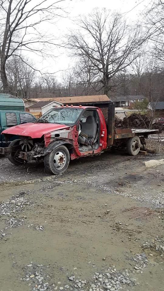 A red truck with its doors open is parked in a dirt lot.