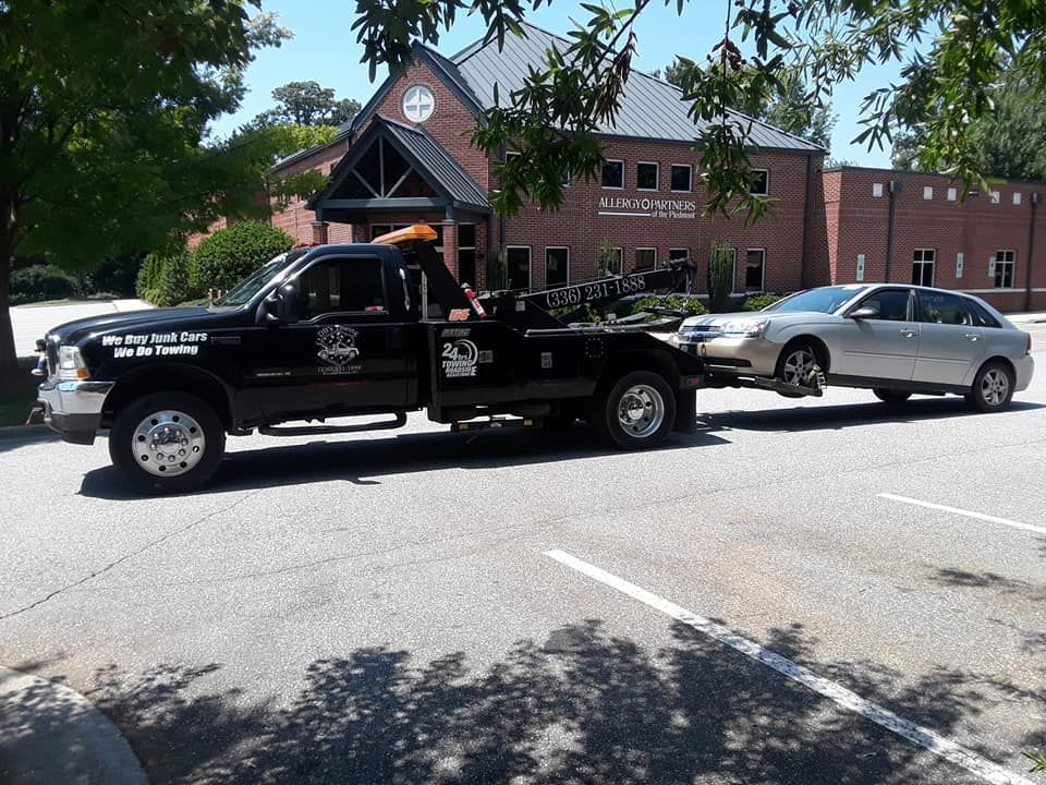 A black tow truck is towing a silver car
