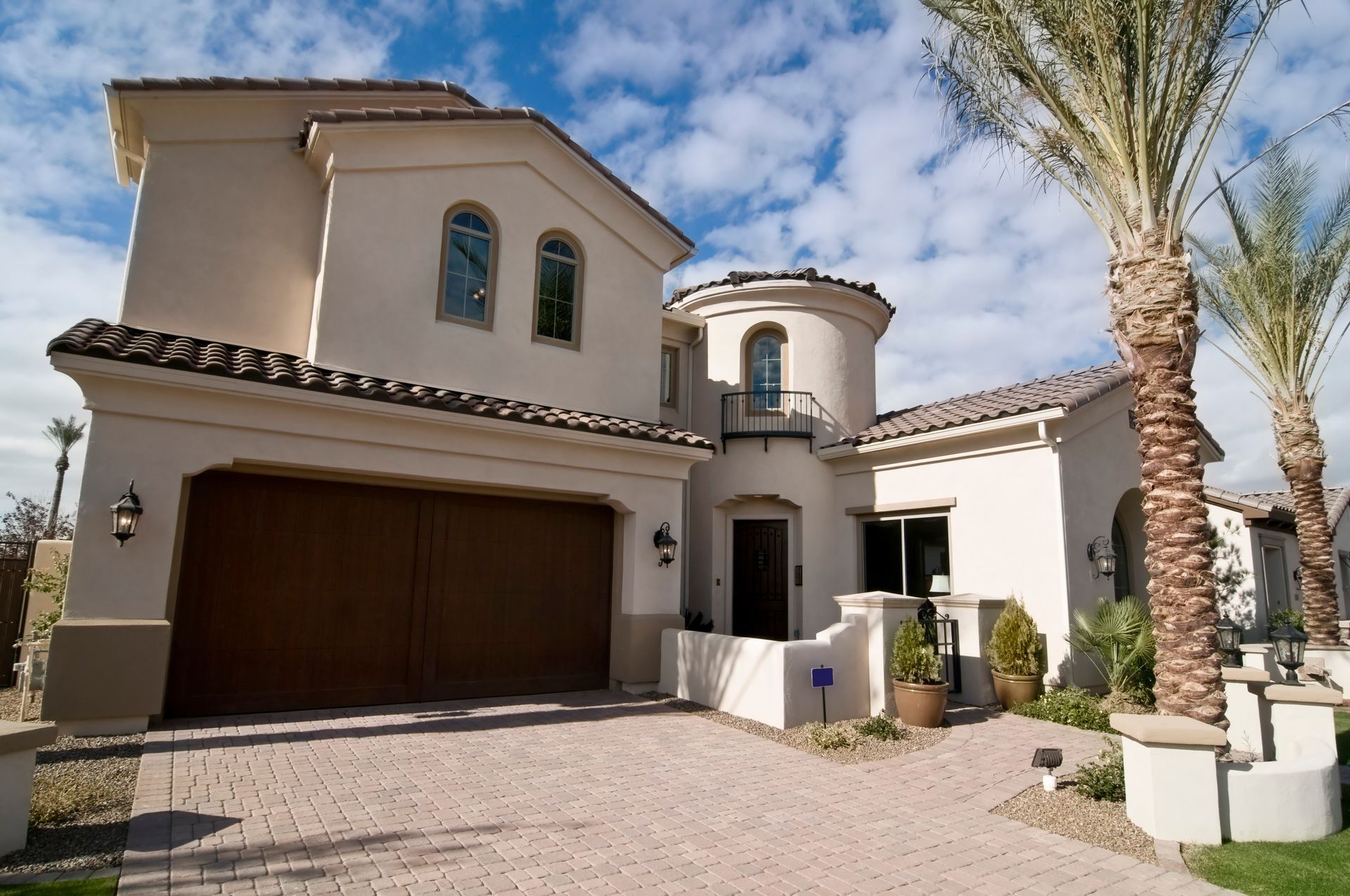 Luxury stucco house exterior with garage, palm trees, and a clear blue sky Luxury stucco house exterior with garage, palm trees, and a clear blue sky