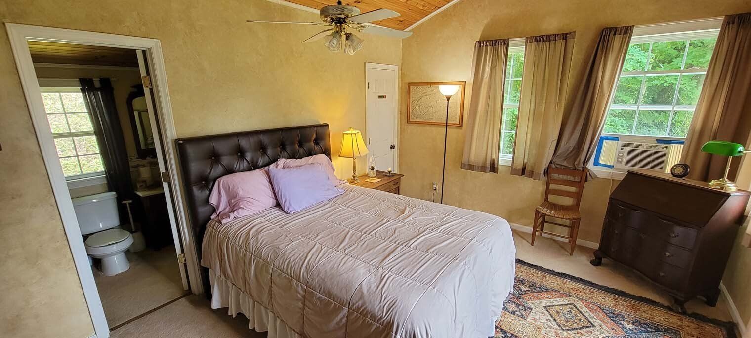 A bedroom with a bed , chair , dresser and window.