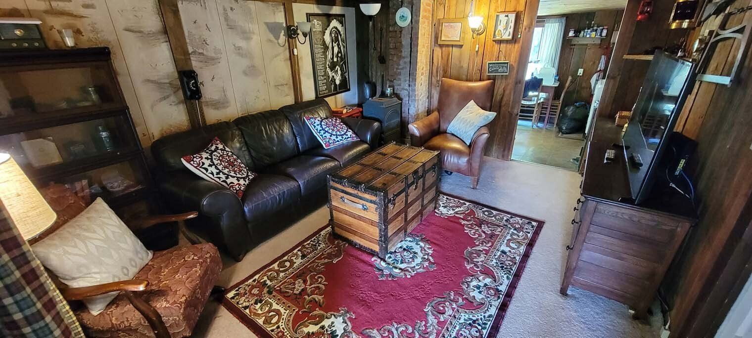 A living room with a couch , chairs , a rug and a trunk.
