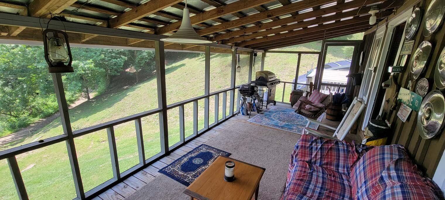 A screened in porch with a couch , table and chairs.