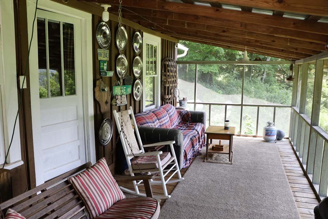 A screened in porch with rocking chairs , a couch , and a table.