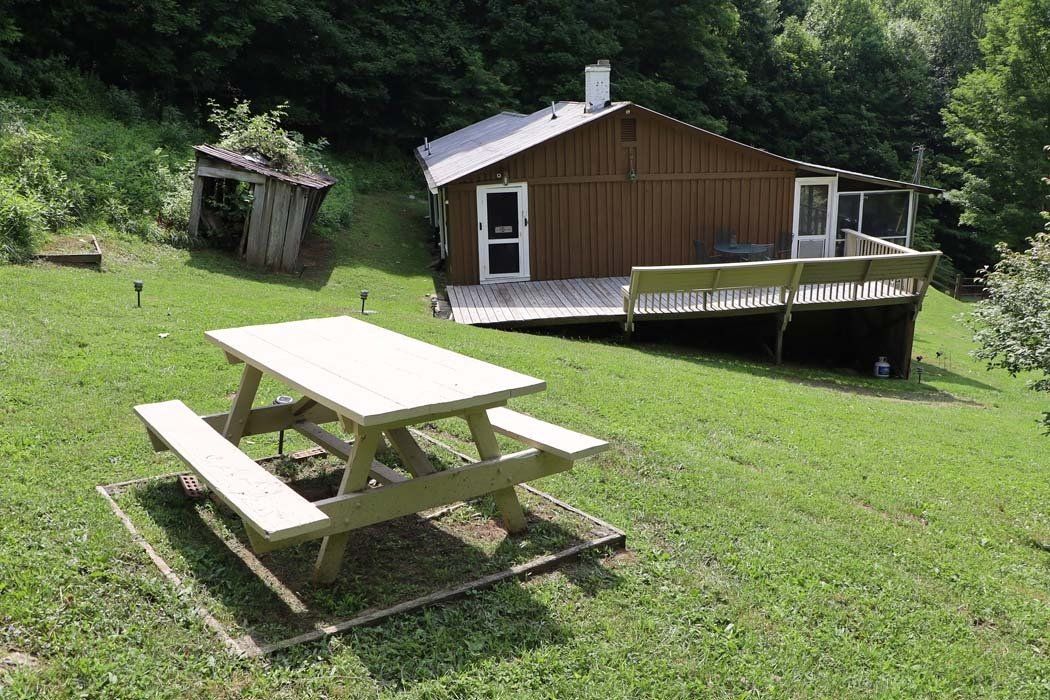 A picnic table is in the grass in front of a house.