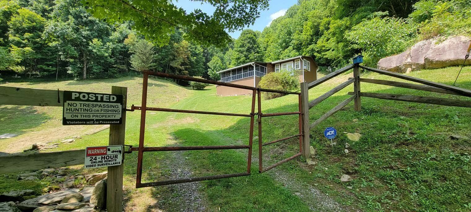 A wooden fence surrounds a grassy field with a house in the background.