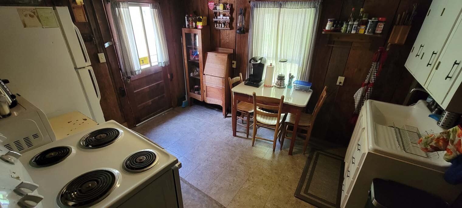 A kitchen with a stove , refrigerator , table and chairs.