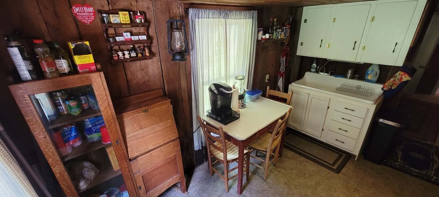 A kitchen with a table , chairs , cabinets and a window.