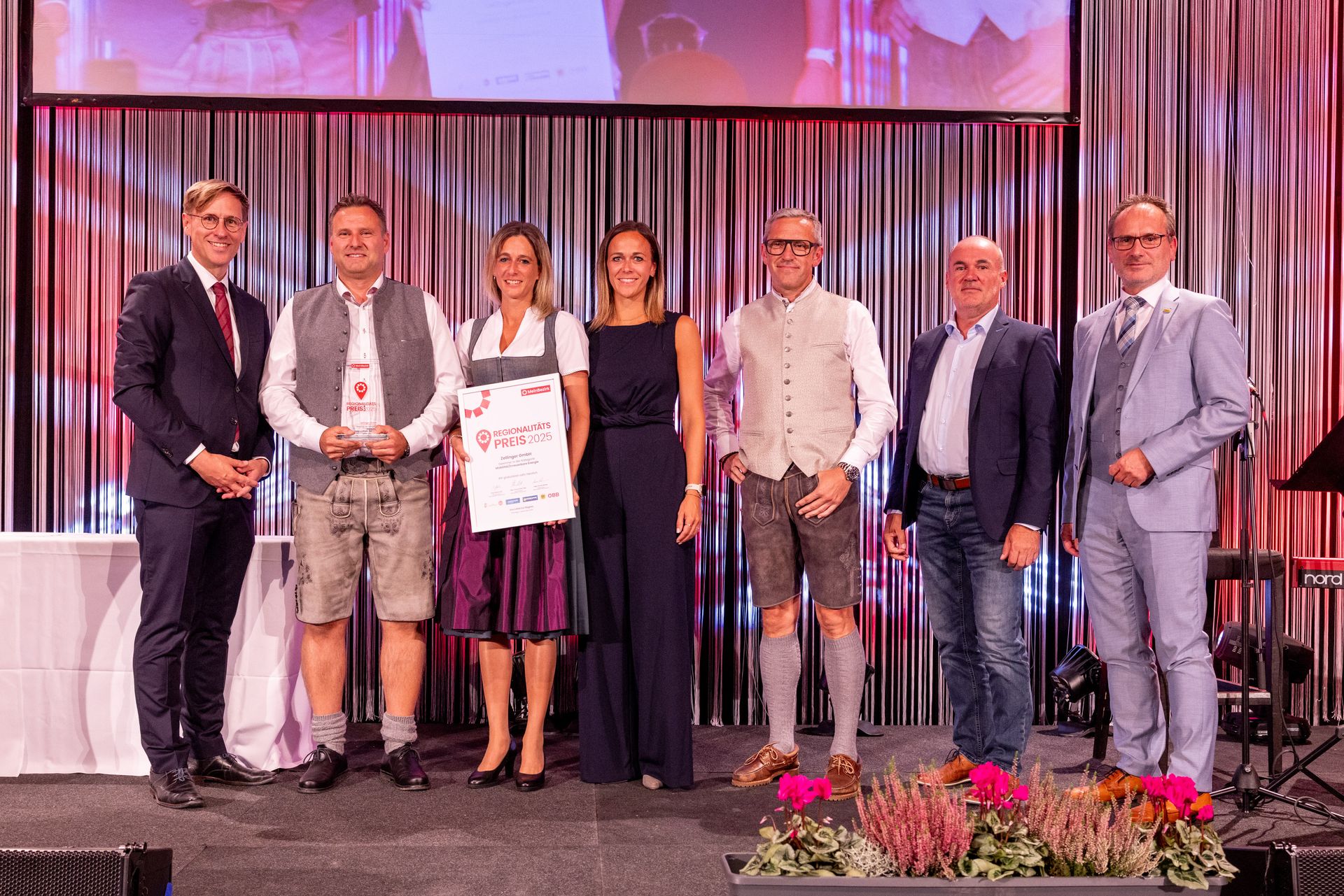 Group of people on stage, some in traditional Bavarian attire, accepting award at event.