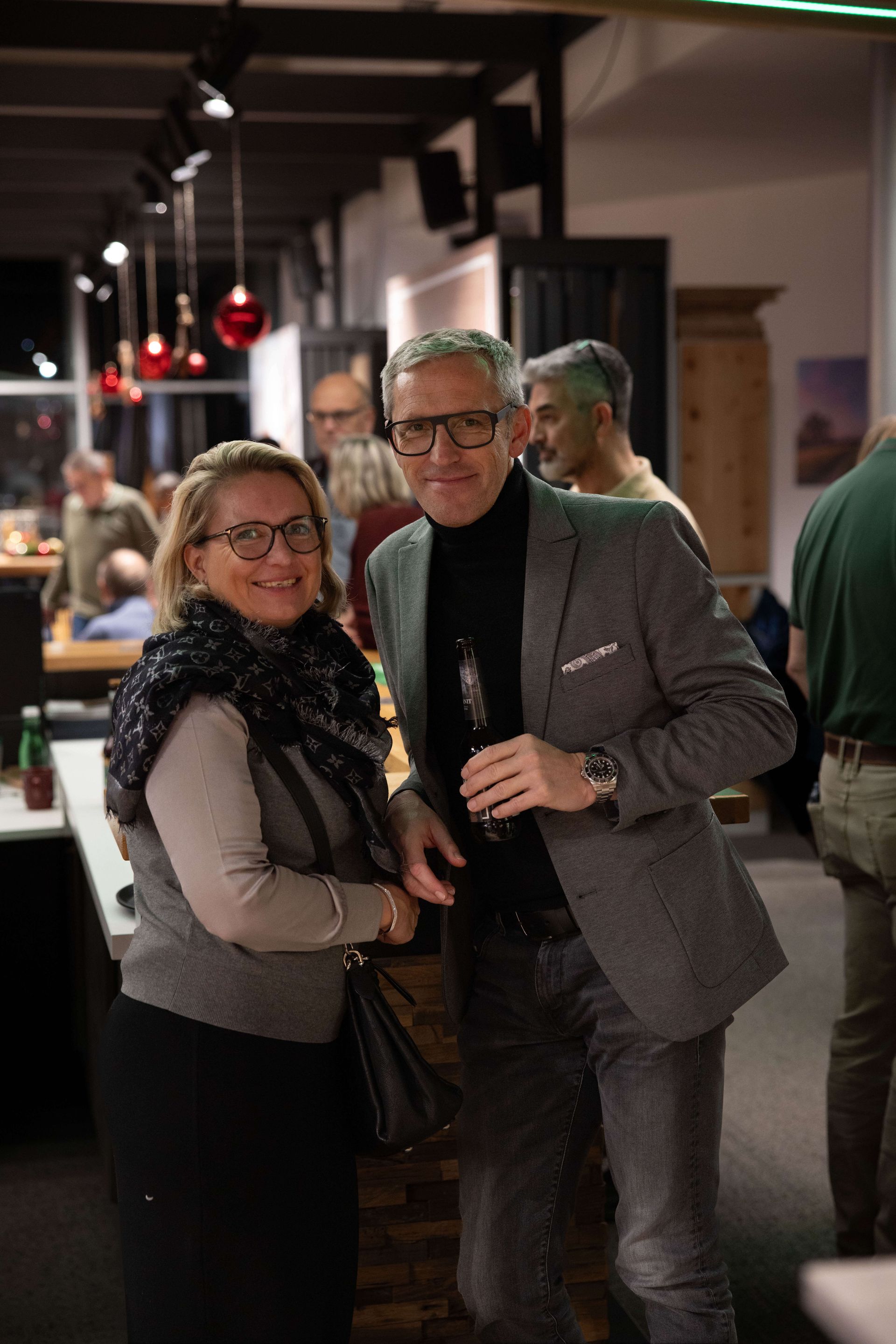 Mann und Frau stehen lächelnd an der Bar. 