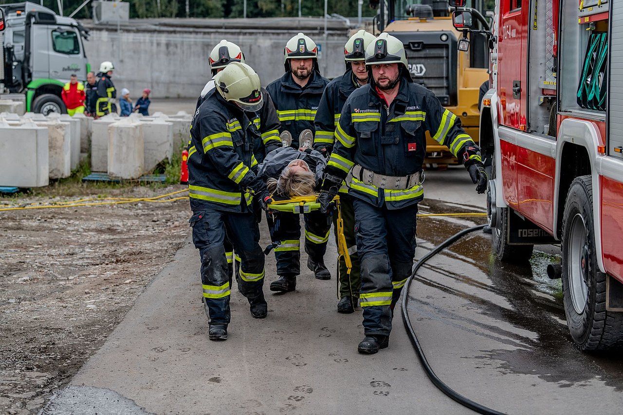 Firefighters carrying a person on a stretcher near a fire truck.