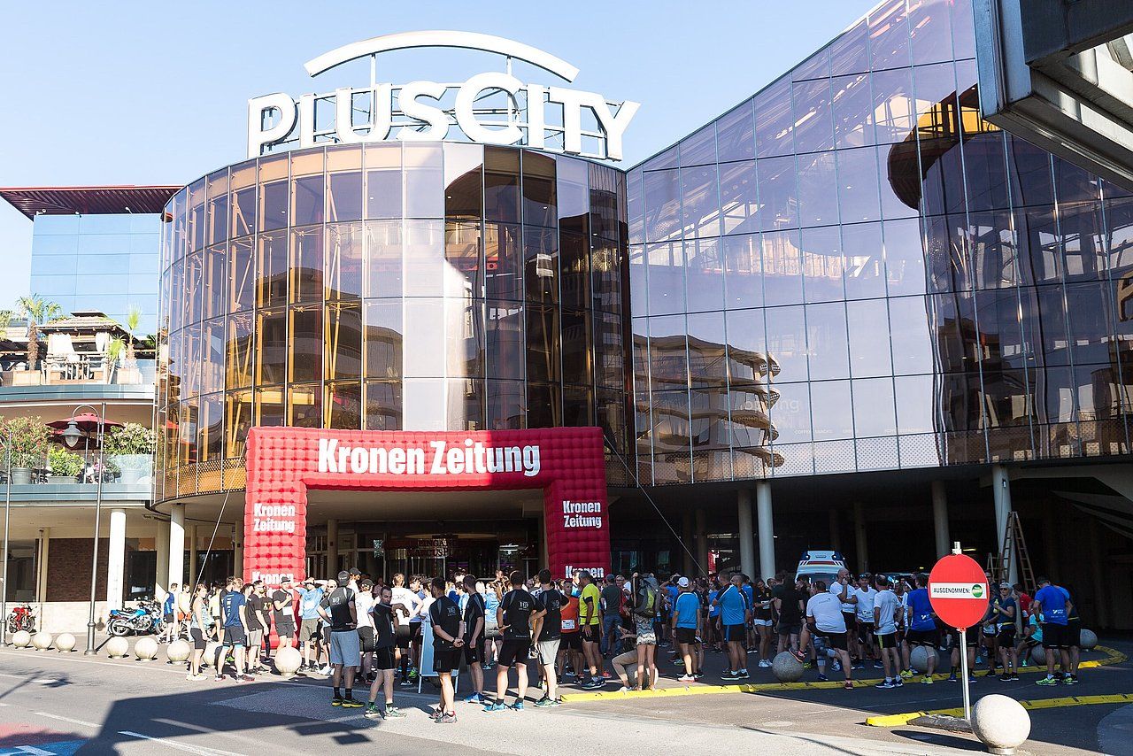 People gather at Plus City mall entrance, under a