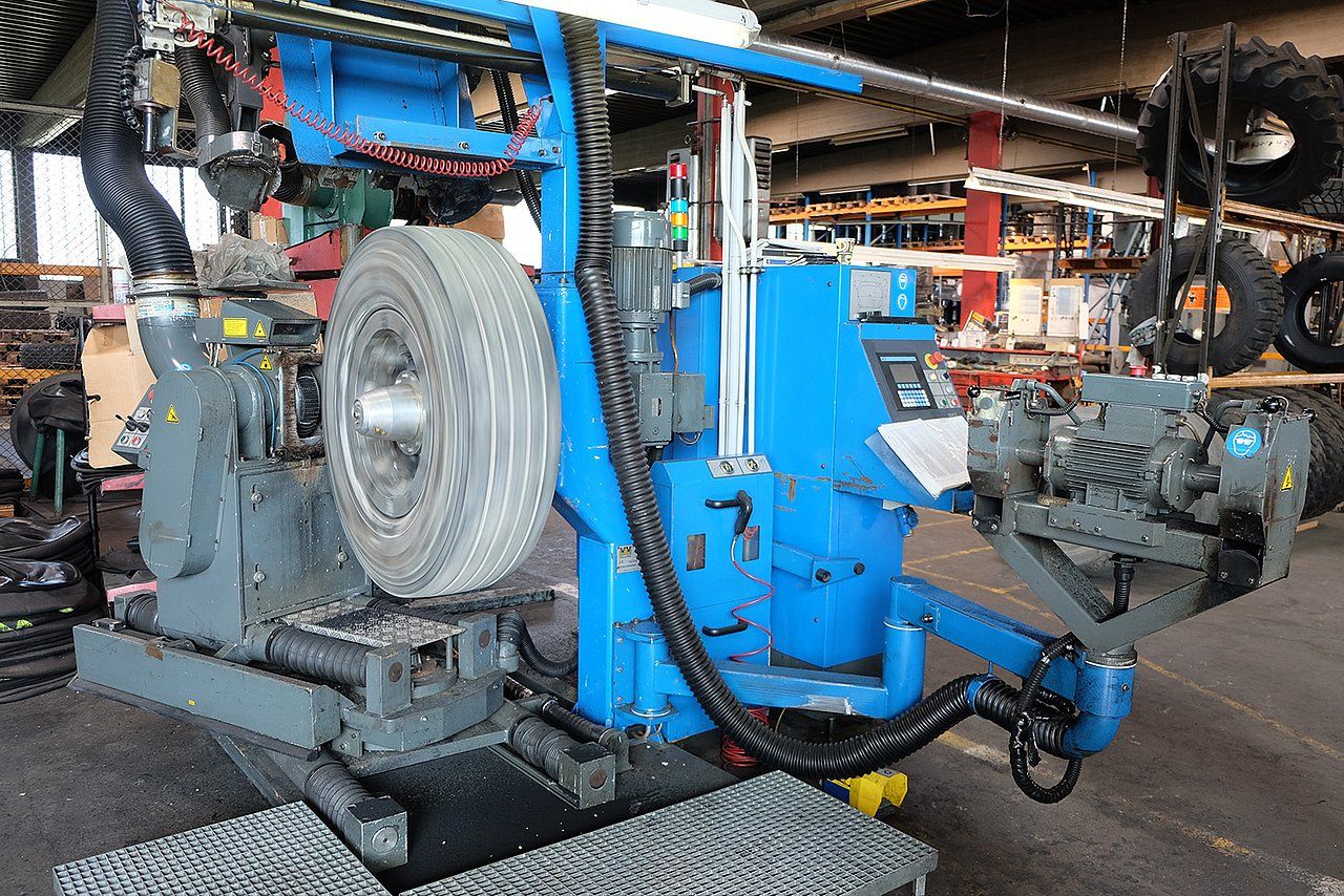 Blue tire mounting machine with a large wheel in a repair shop.